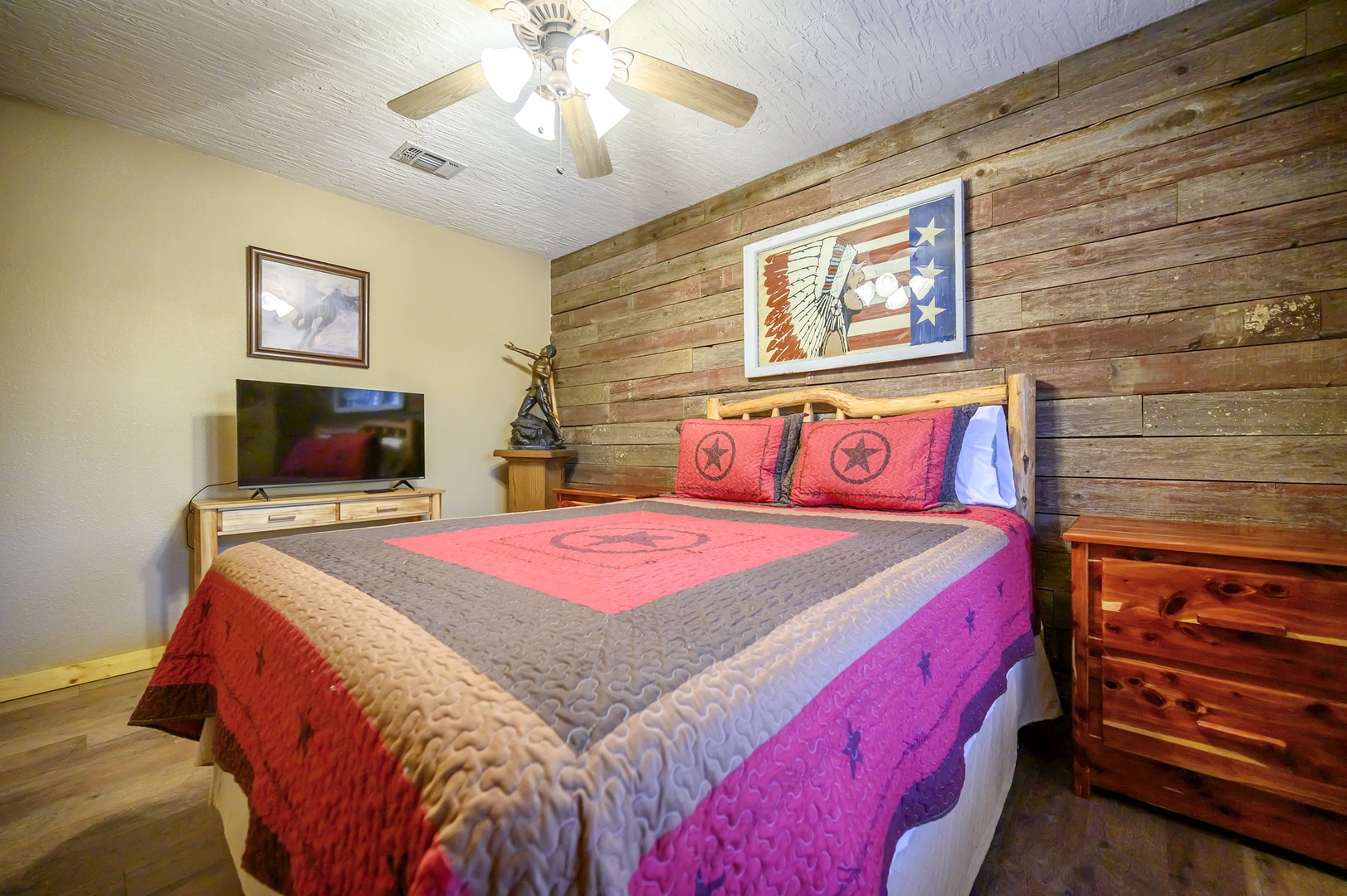 Unwind in your cozy western-themed bedroom featuring rustic wood accents, patriotic décor, and modern amenities for perfect Texas-style comfort.