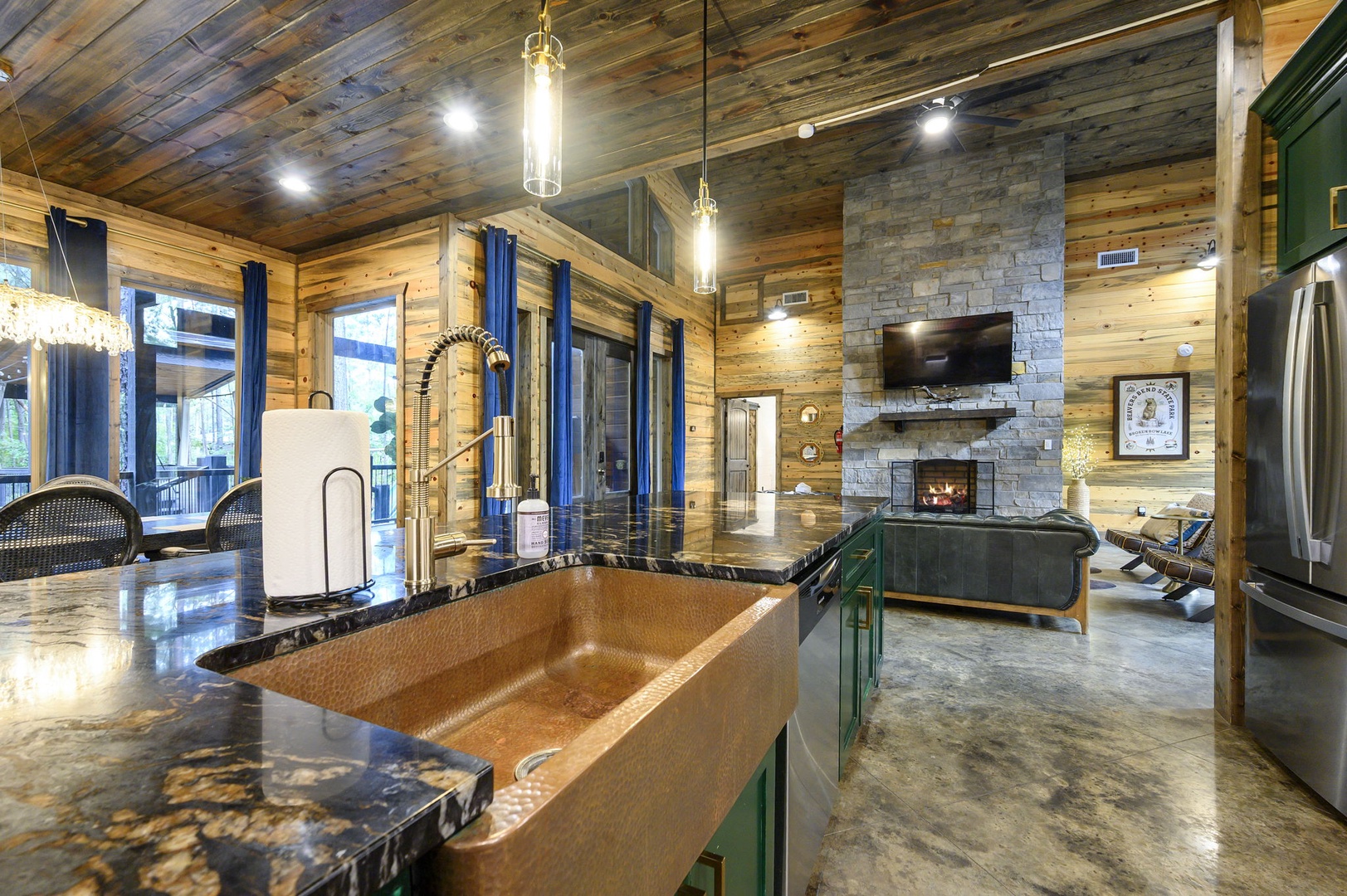 Gather around the hammered copper sink and gleaming granite island, where rustic warmth meets modern luxury beneath soaring reclaimed wood ceilings—your cozy mountain retreat awaits.