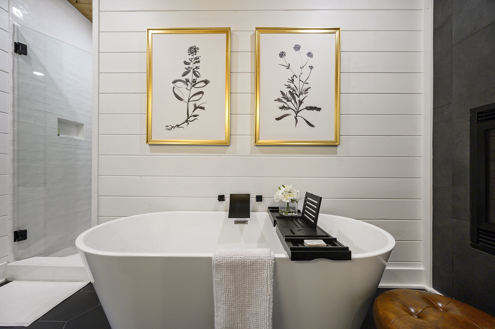 Unwind in your luxurious freestanding tub, surrounded by elegant botanical art and pristine white shiplap walls that create the perfect spa-like sanctuary.