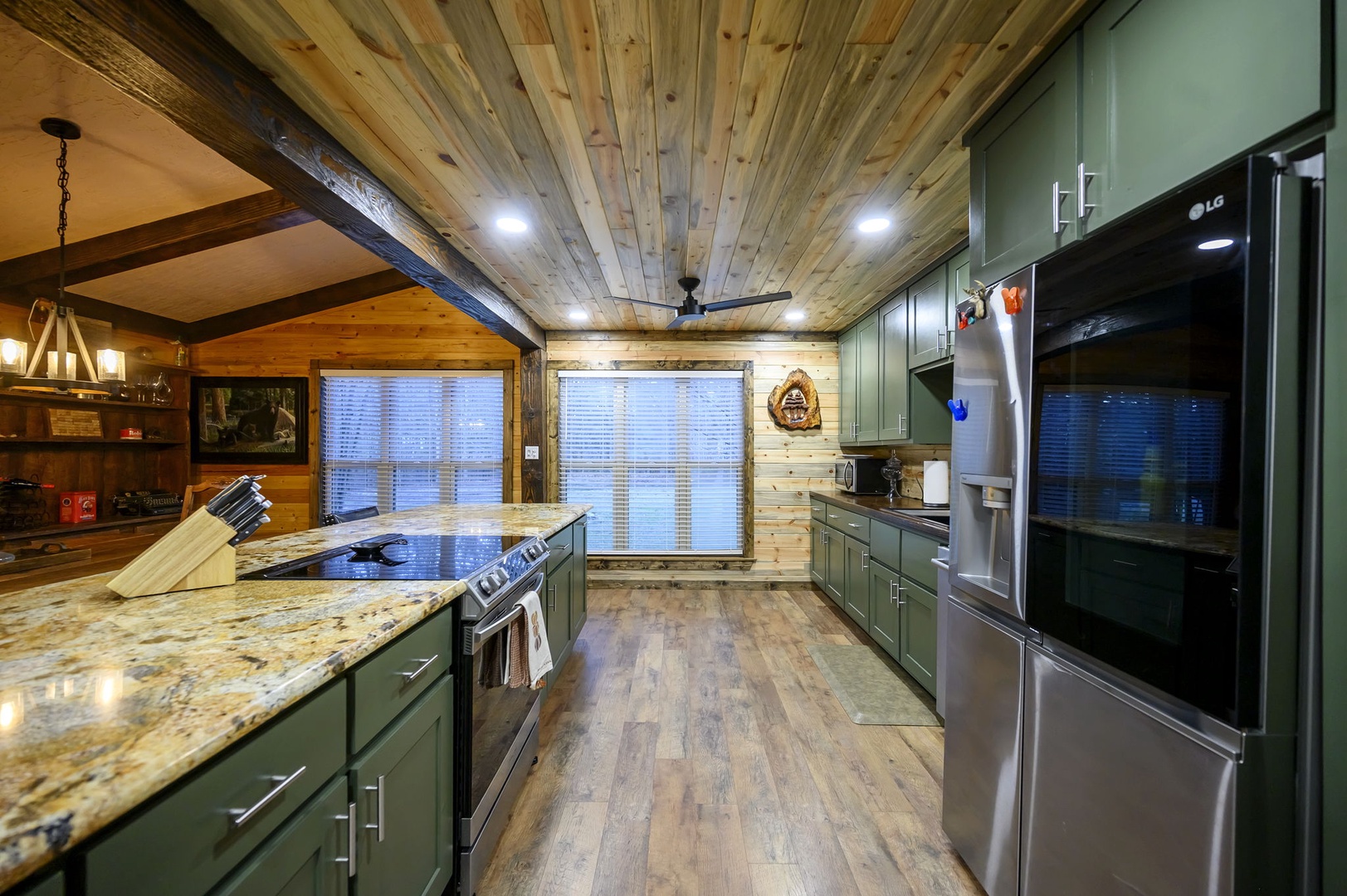 Your fully-equipped kitchen blends rustic charm with modern convenience, featuring granite countertops and stainless steel appliances beneath stunning reclaimed wood ceilings.