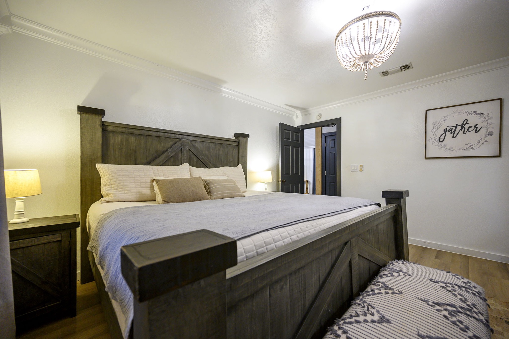 Sink into this rustic-chic bed where weathered wood meets soft linens. Your chandelier-lit sanctuary awaits peaceful nights.