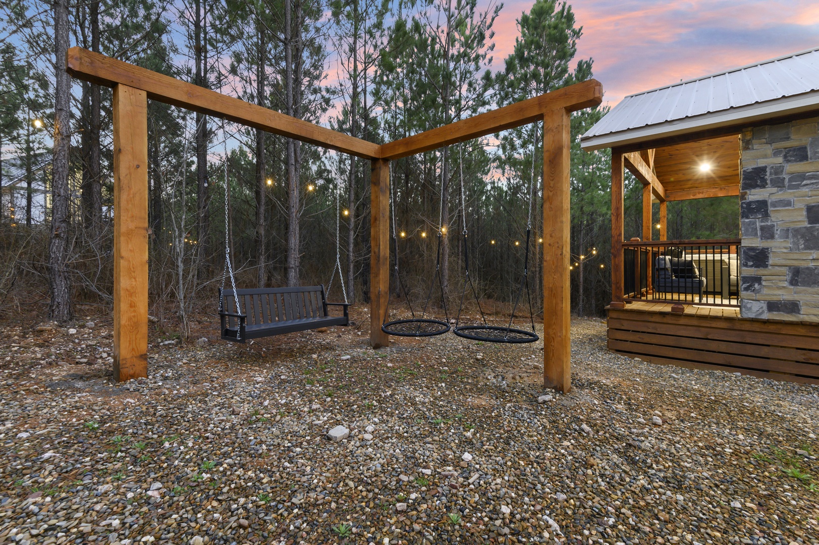 Unwind on the swing set as twilight paints the sky, with twinkling lights creating magical evenings in your private forest retreat.
