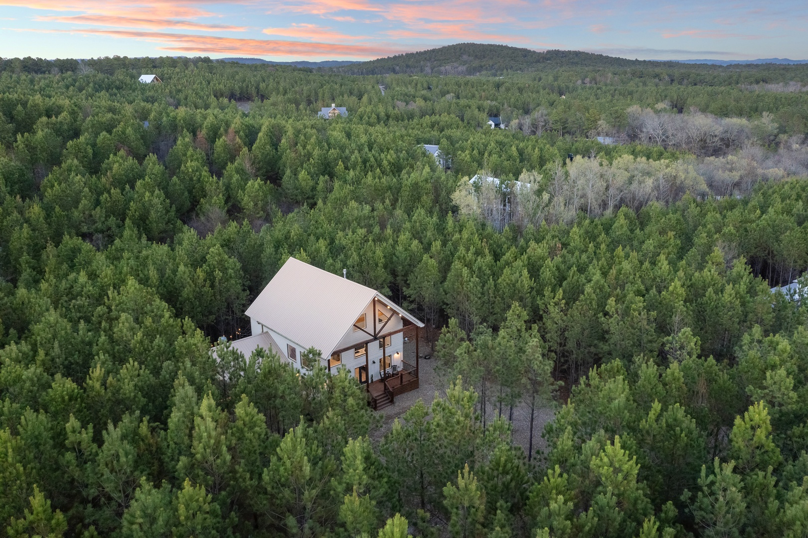 A stunning modern cabin nestled in pristine forest surroundings, offering complete privacy and tranquil mountain views at sunset.
