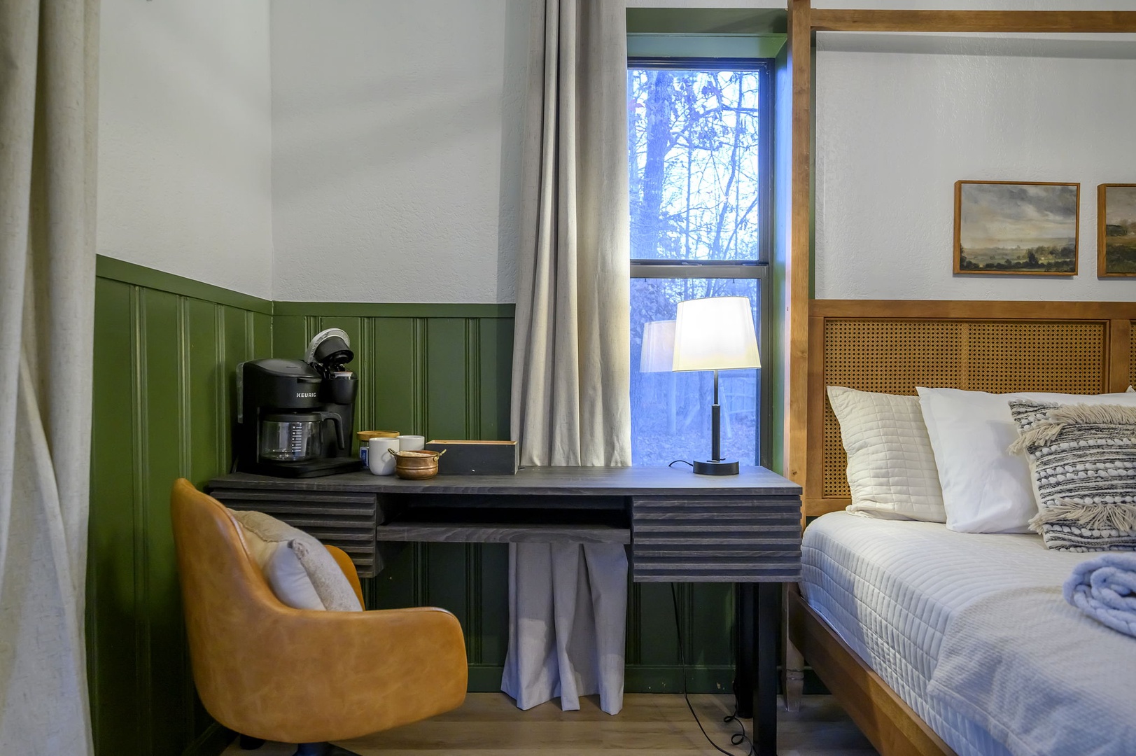 Relax in your stylish room featuring a cozy workspace, coffee maker for morning brews, and comfortable seating by the window with peaceful forest views.
