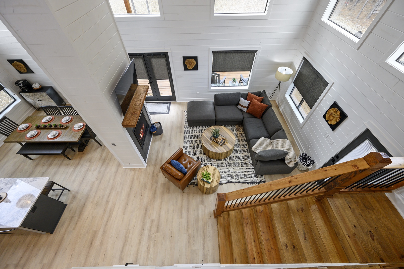 Gaze down at your stylish open-plan retreat featuring a cozy sectional, modern fireplace, and skylights flooding the space with natural light.