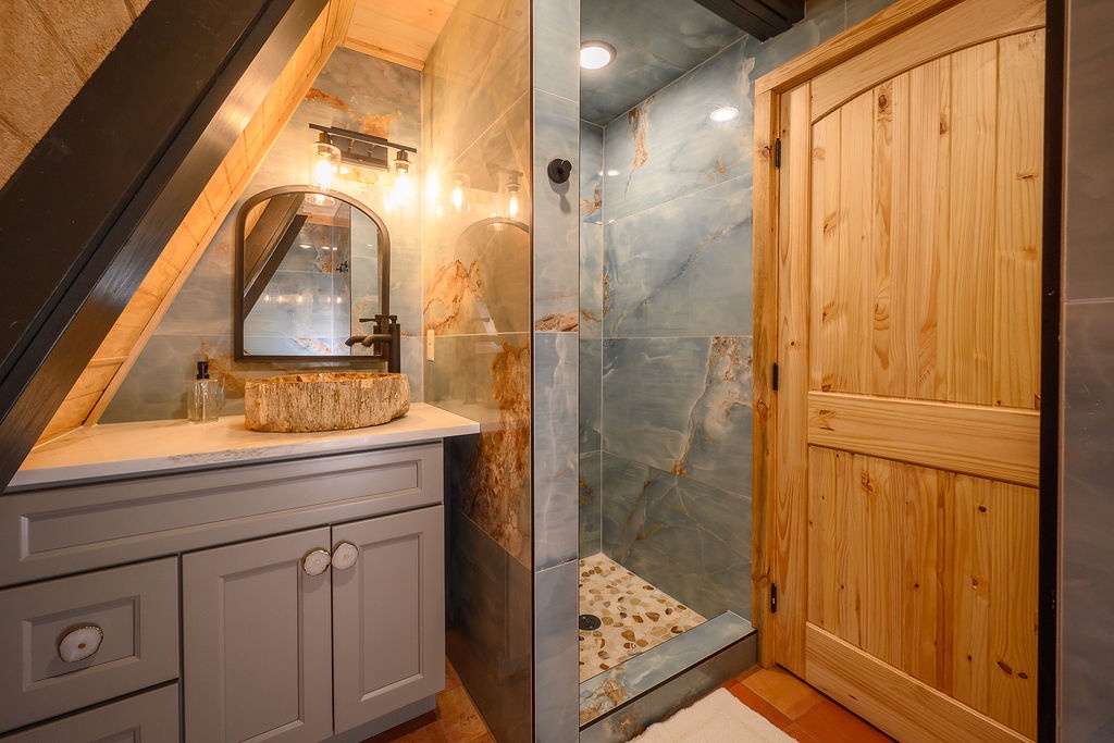 Your private bathroom blends rustic charm with modern elegance. The statement stone sink and sleek glass-enclosed shower create a spa-like retreat after a day of exploring.