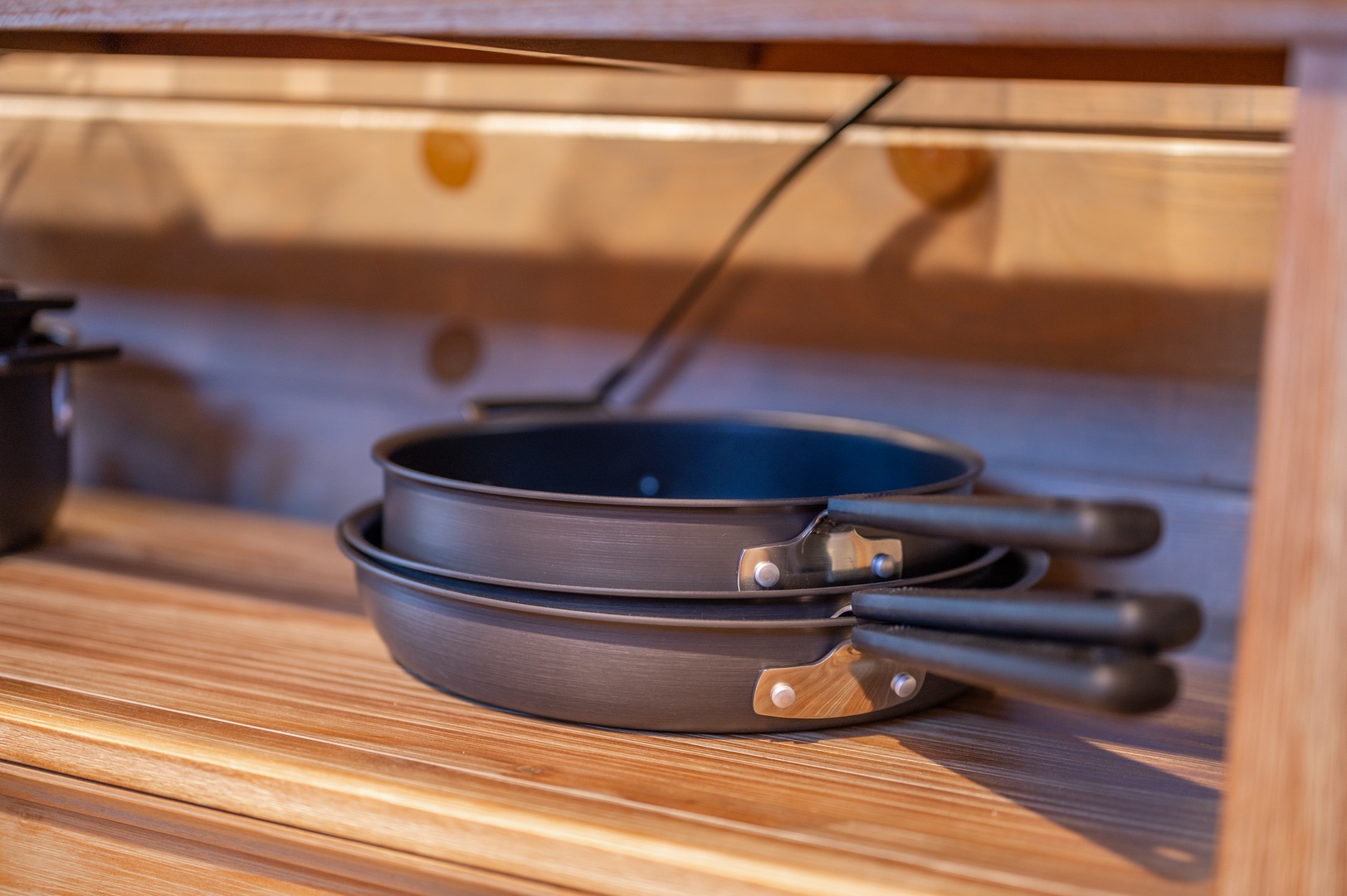 Your well-equipped kitchen awaits with quality cookware neatly organized in custom wooden storage, making meal preparation a joy.