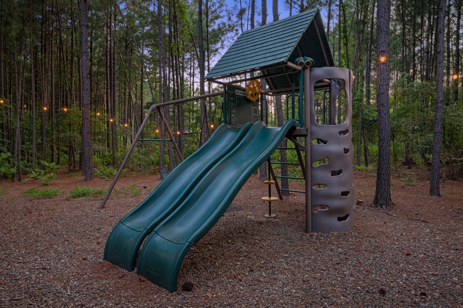 A playground nestled among tall pines offers a fun outdoor space for the little ones during your stay.