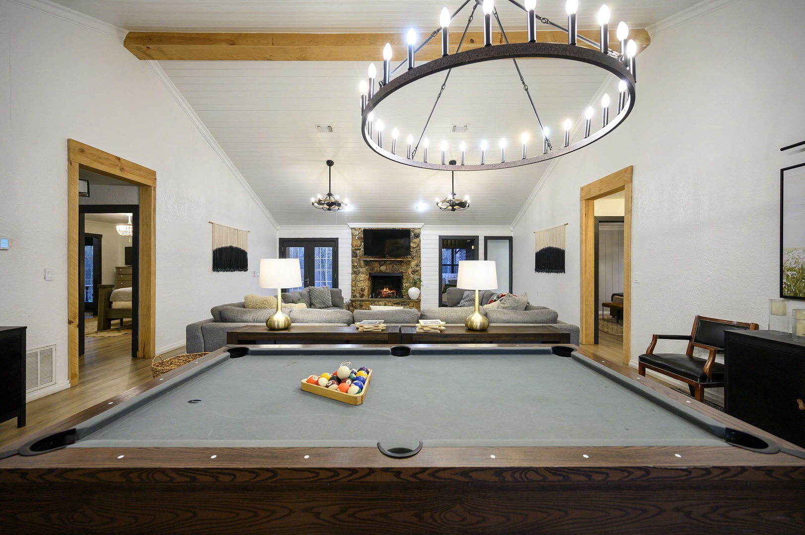Your perfect game room awaits with a professional pool table beneath a stunning chandelier, cozy seating by the fireplace for post-game relaxation.