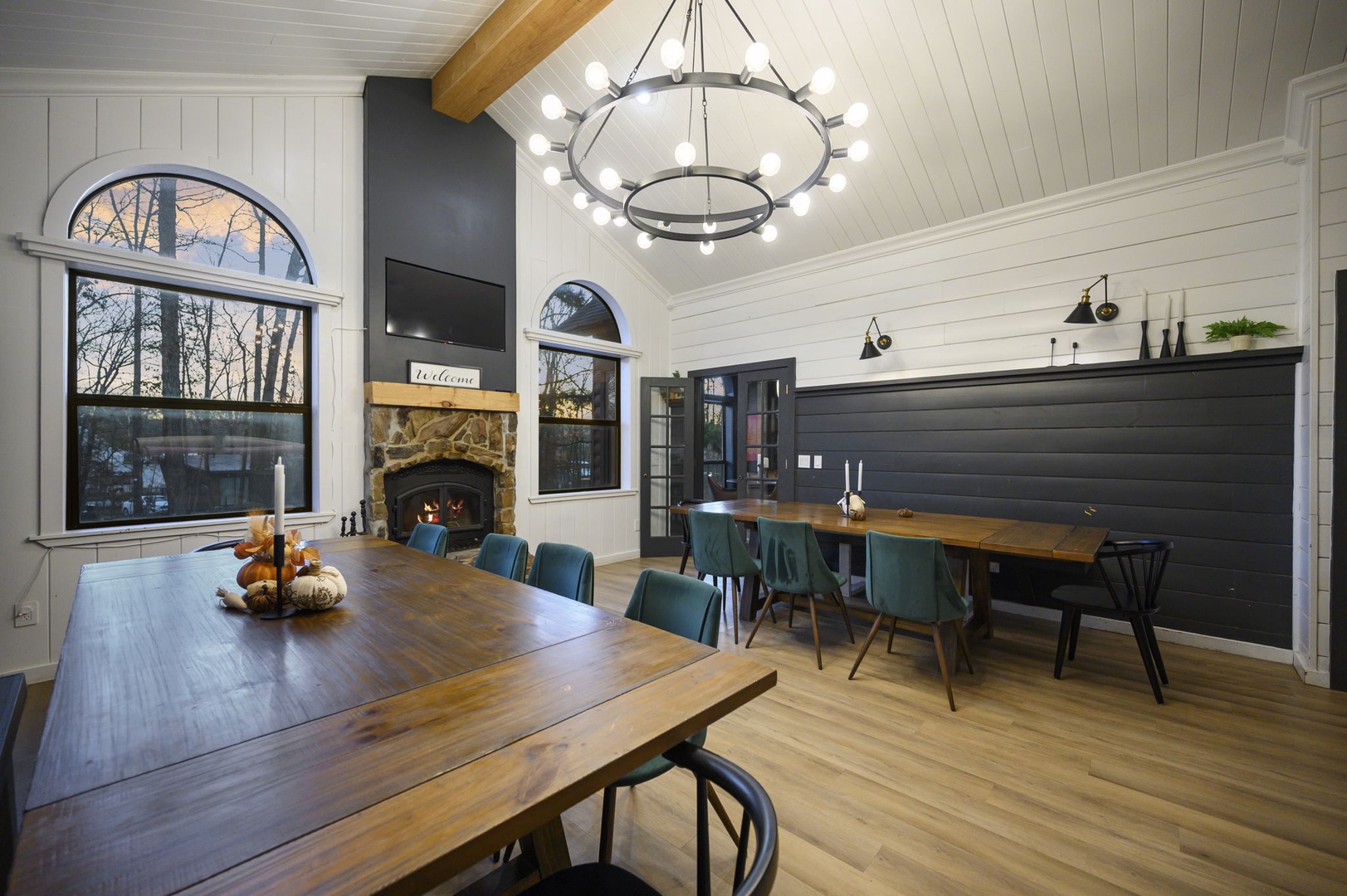 Gather around rustic wood tables in this elegant dining space, where cozy fireplace warmth meets modern style beneath soaring ceilings.
