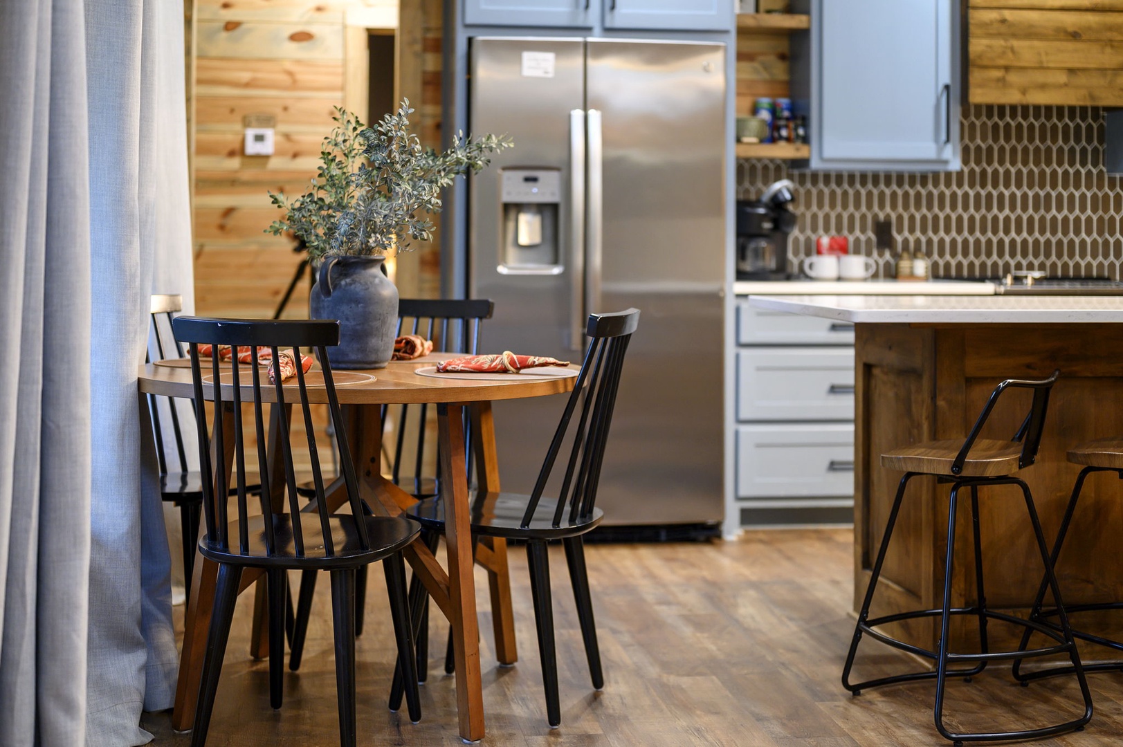 Gather around your welcoming dining table, perfectly positioned between the cozy living area and the full modern kitchen, complete with sleek stainless appliances and warm wood accents.