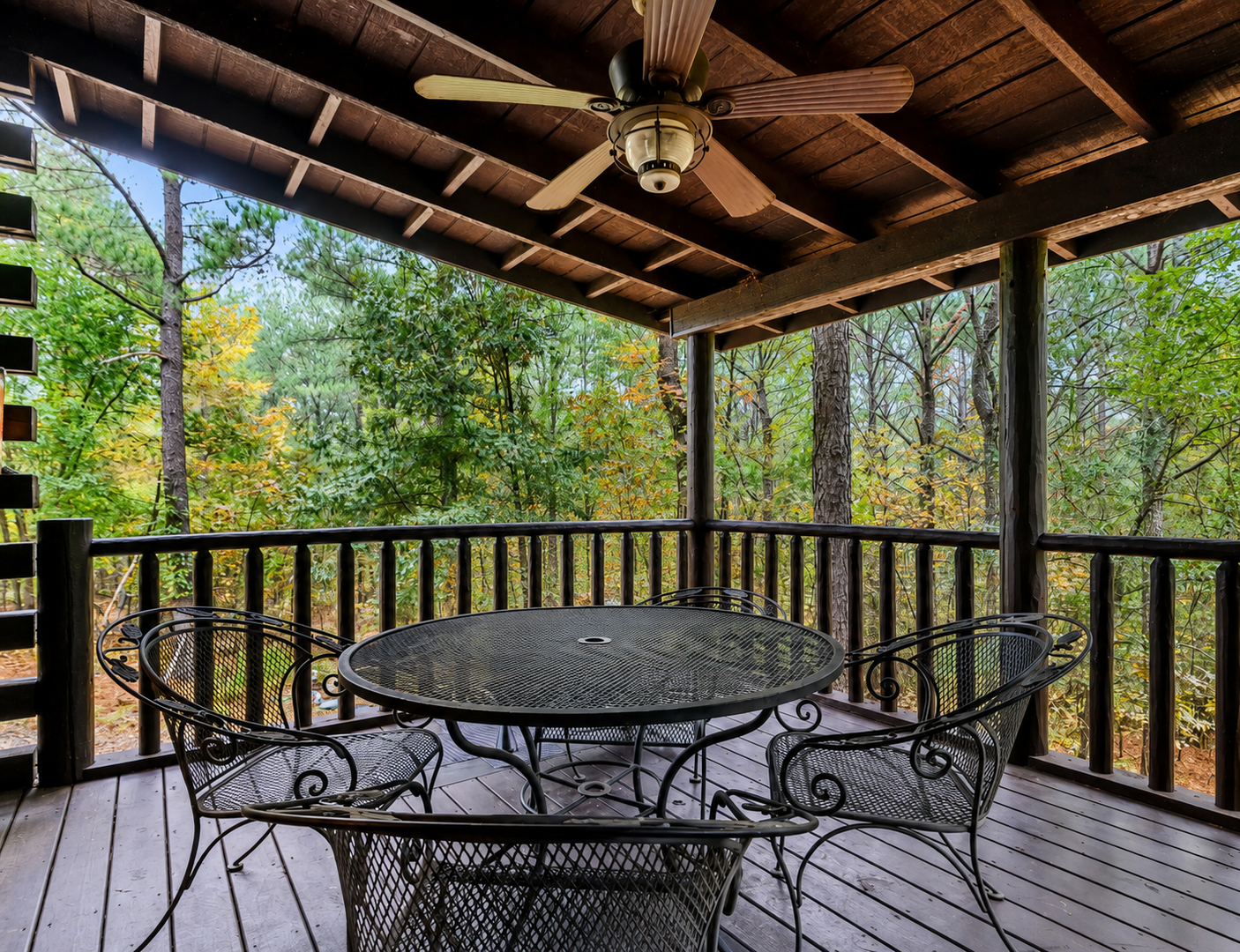 Picture yourself sipping morning coffee at this inviting table, cooled by the ceiling fan above while you soak in peaceful forest views. The perfect spot to unwind and reconnect with nature.