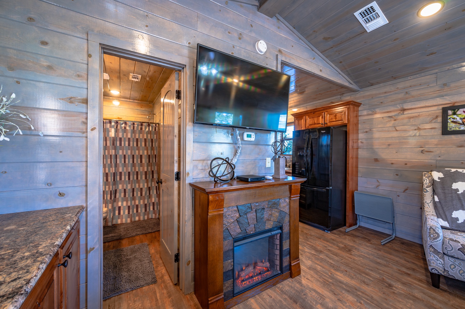Cozy up by your electric fireplace while watching TV in this rustic cabin retreat with warm wood walls.