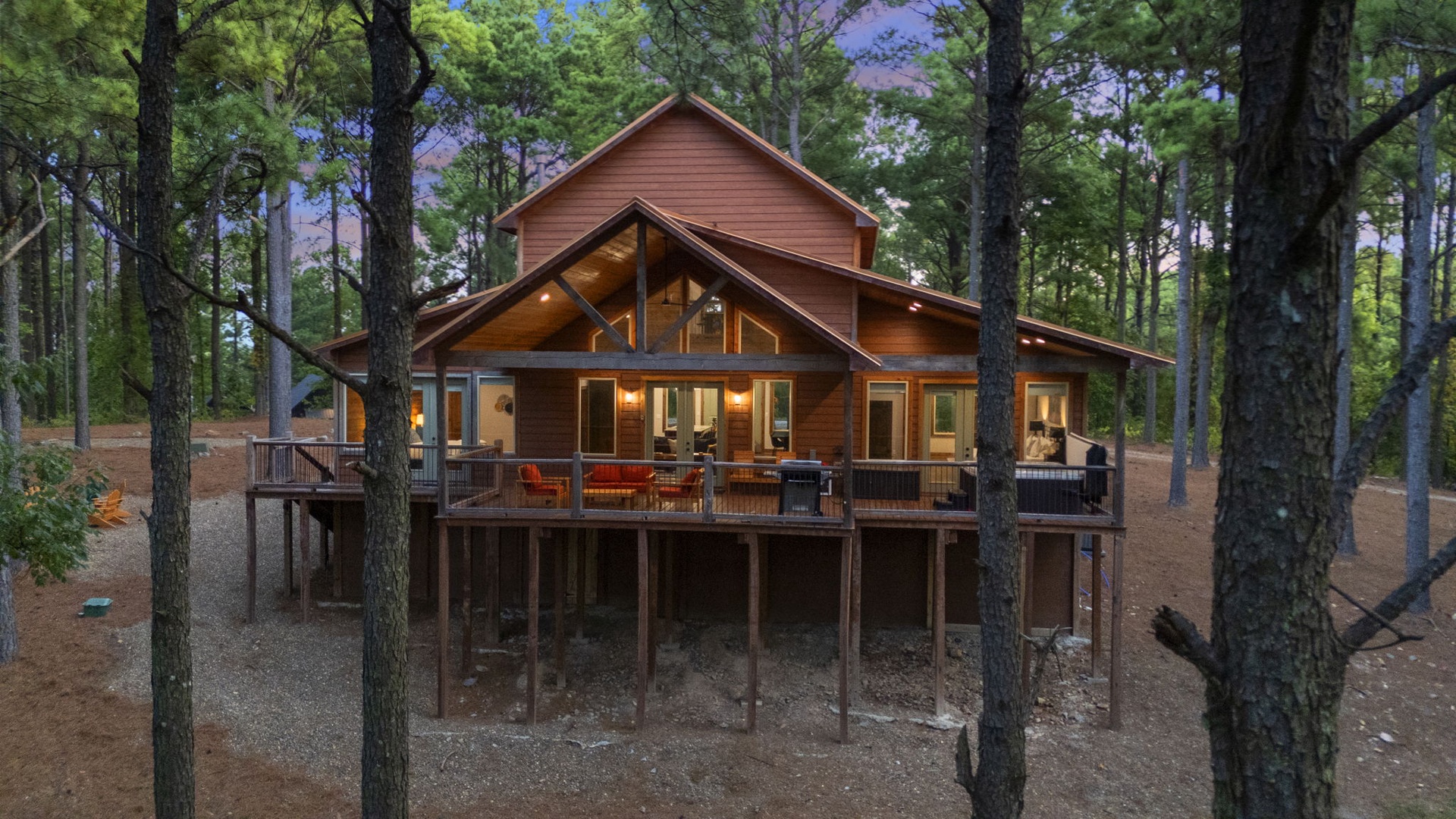 A peaceful cabin retreat nestled in the woods, elevated above the forest floor with a spacious deck for outdoor dining and relaxation.