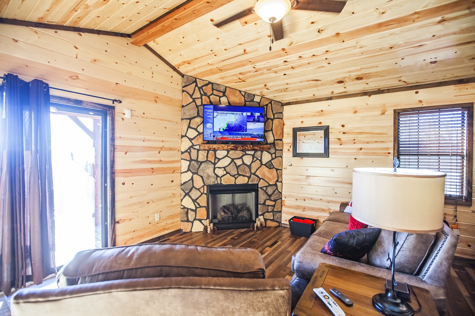 Unwind in your cozy cabin living room with stone fireplace, flat-screen TV, and rustic charm after mountain adventures.