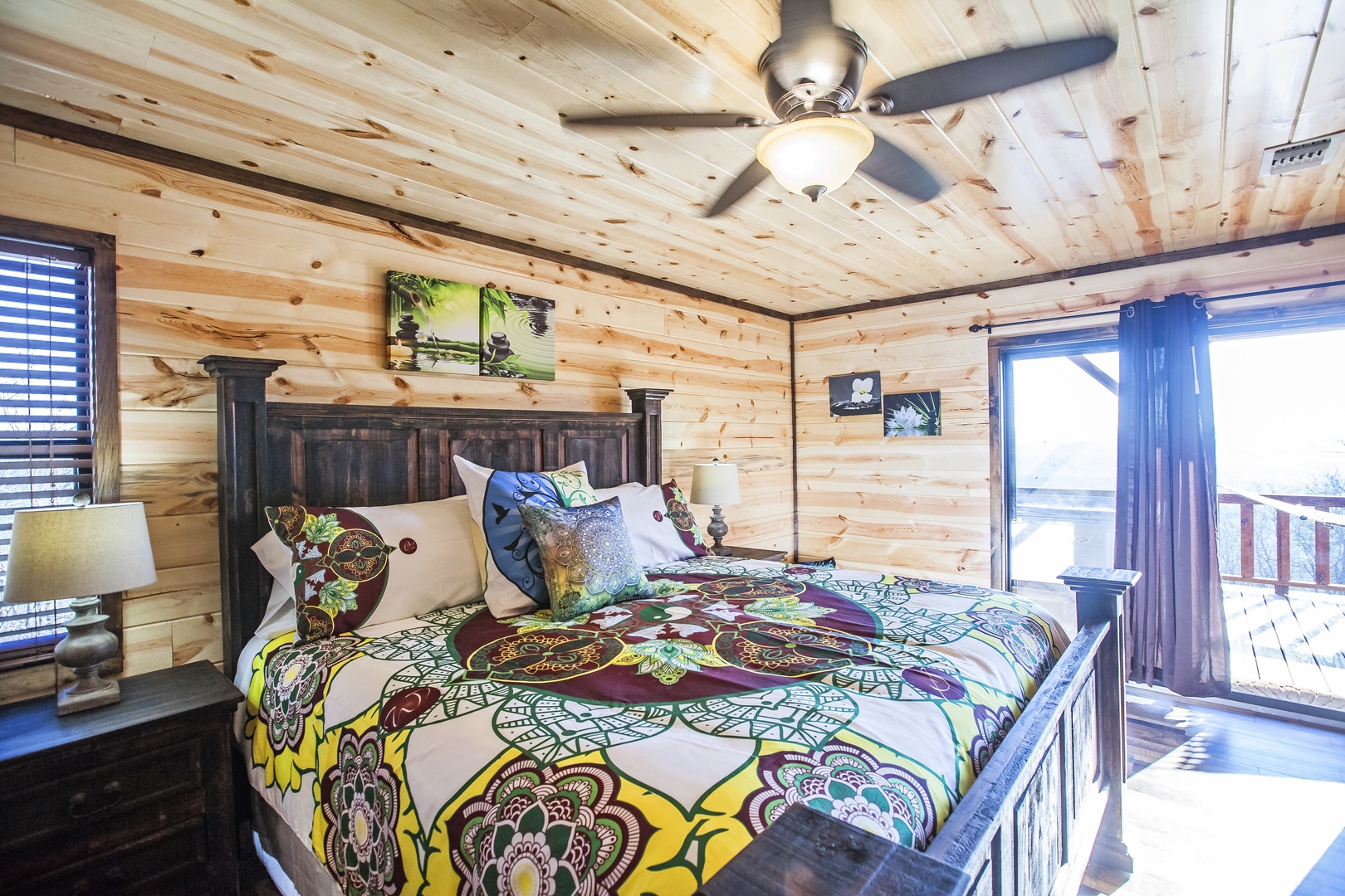 Wake up in your cozy log cabin bedroom with rustic charm and colorful bedding, enjoying mountain views through your private balcony doors.