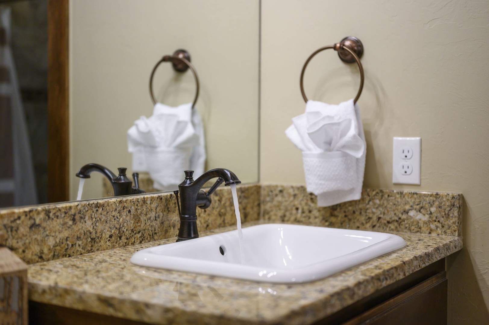 Freshen up at your elegantly appointed vanity with a granite countertop, stylish bronze fixtures, and plush towels ready for your arrival.