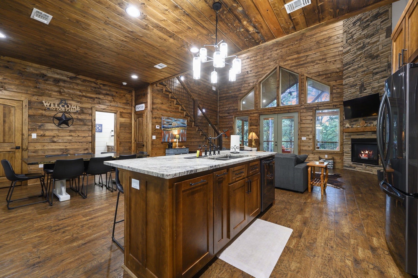 Step into your inviting great room where warm wood beams soar overhead and a cozy fireplace awaits. The spacious kitchen island offers plenty of room to gather, while picture windows frame peaceful forest views that bring nature right to your door.