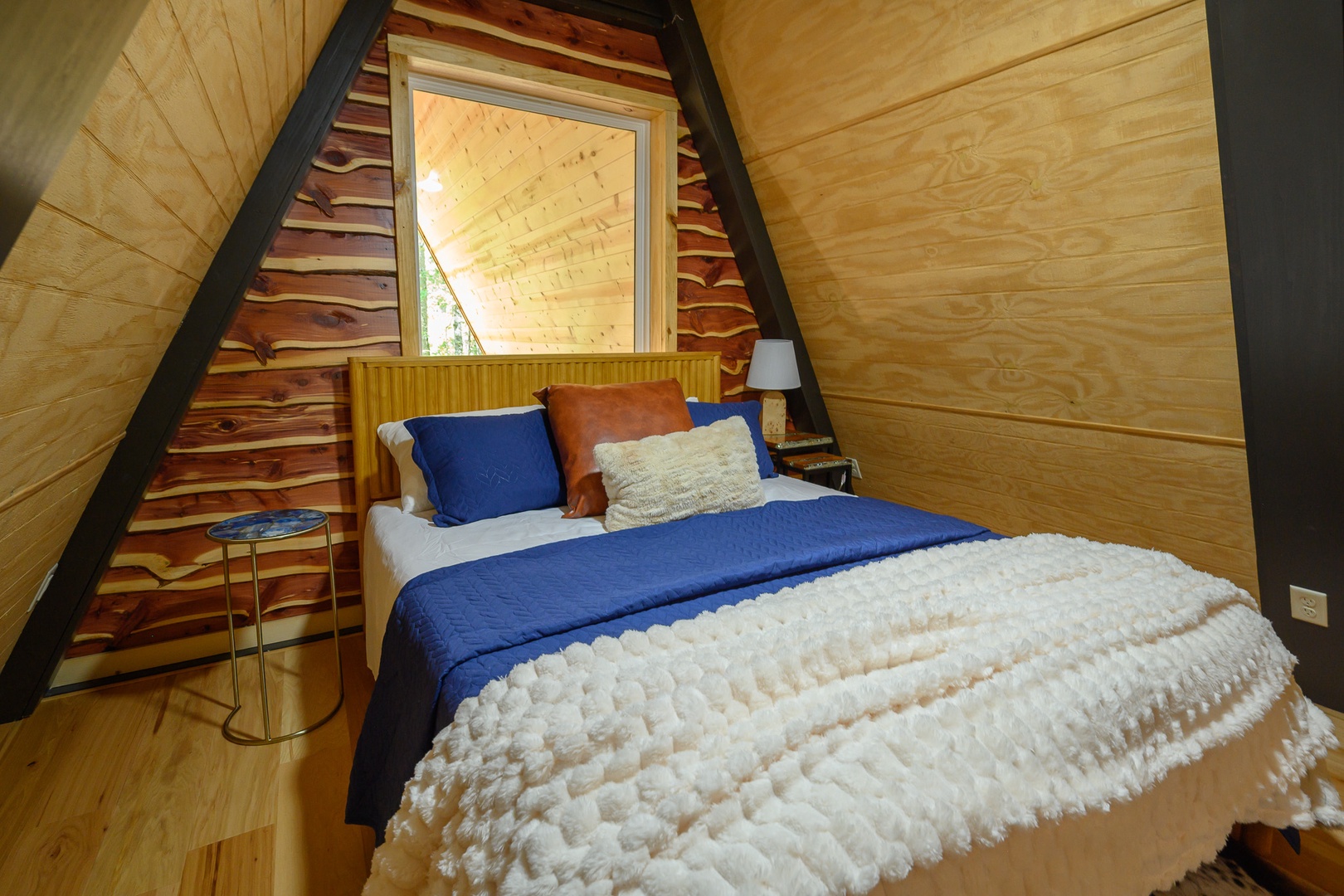 Cozy up in this inviting A-frame loft bedroom, where warm wood tones and vaulted ceilings create a peaceful retreat perfect for restful nights.