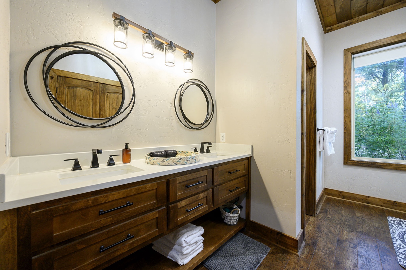Step into your private spa-like retreat, where dual vanities and warm wood tones invite you to unwind. Fluffy towels await, and natural light filters through the window to brighten your morning routine.