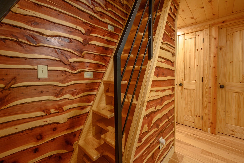 Handcrafted cedar stairs with black metal railing showcase the natural beauty of the wood.