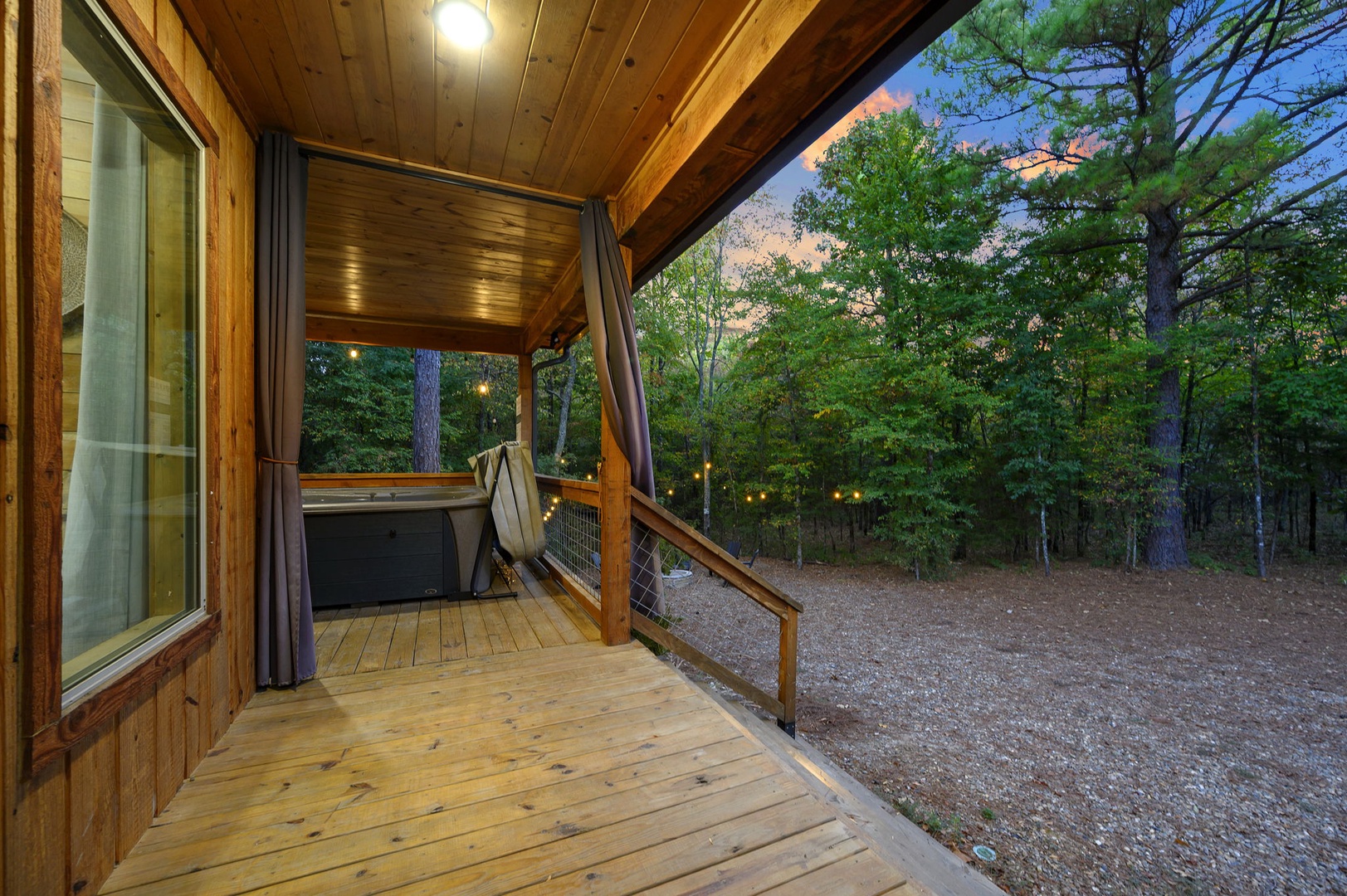 Sunset paints the sky in soft pastels beyond your private deck, where a peaceful forest retreat awaits. Enjoy the hot tub surrounded by towering trees and the gentle sounds of nature.