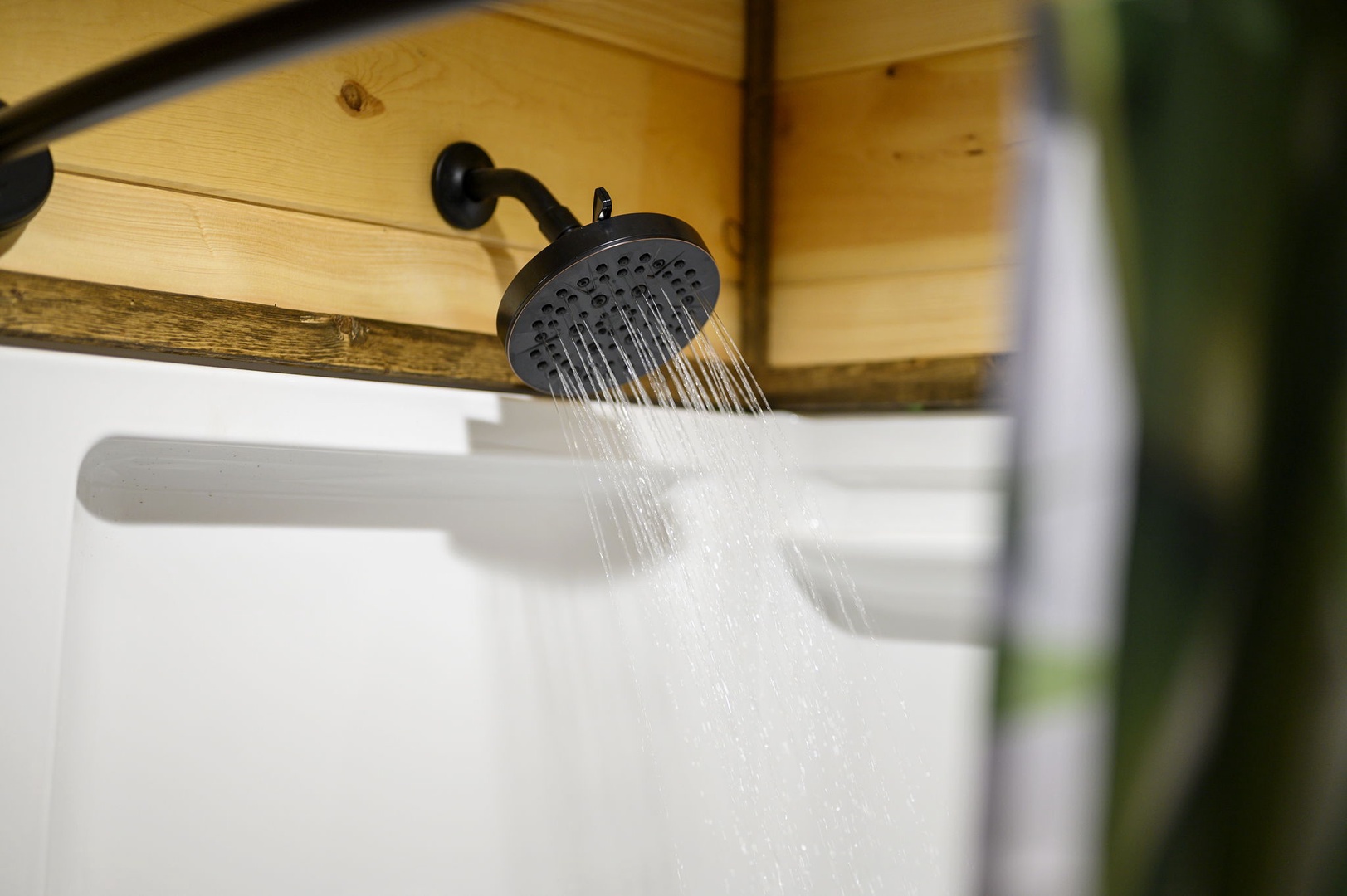Rinse off after a day of adventure under this rustic overhead shower, where natural wood beams and smooth water flow combine for a refreshing retreat just for you.