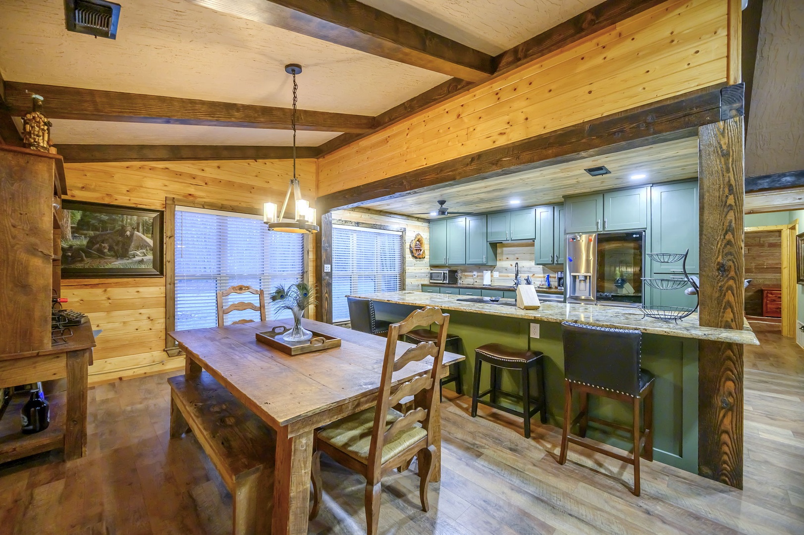 Gather around the rustic dining table where warm wood beams frame your mountain retreat moments, while the fully-equipped kitchen awaits your culinary adventures.