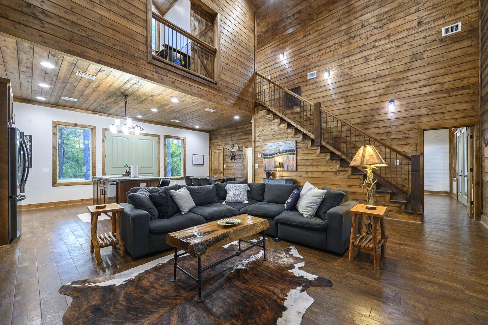 Unwind in your spacious cabin living room, where soaring wood-planked ceilings and natural light create a warm, rustic retreat perfect for gathering after a day of adventure.