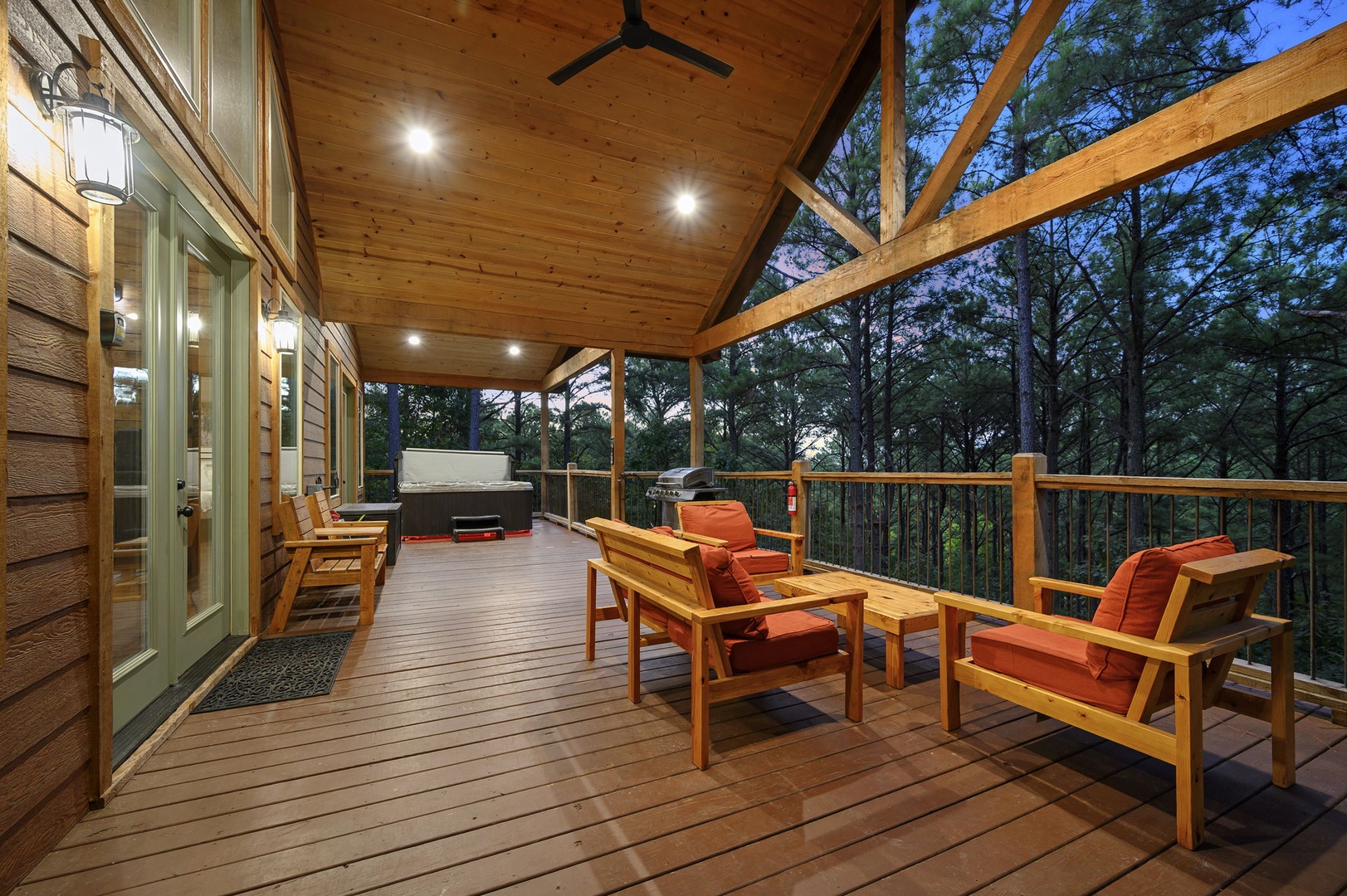 Your private covered deck invites relaxation with cozy seating and a hot tub surrounded by peaceful forest views—perfect for unwinding under the stars.