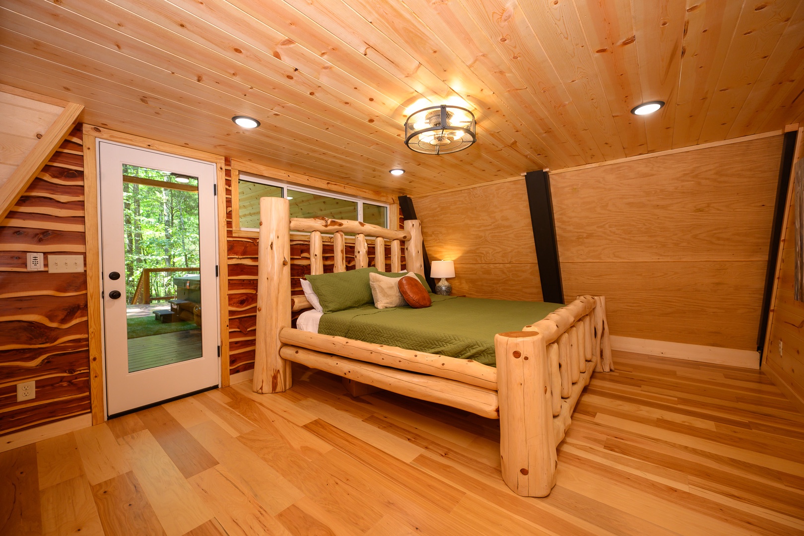 Step into your cozy retreat with warm wood surroundings and a handcrafted log bed that invites restful sleep. Natural light streams through the glass door, connecting you to peaceful forest views just steps away.