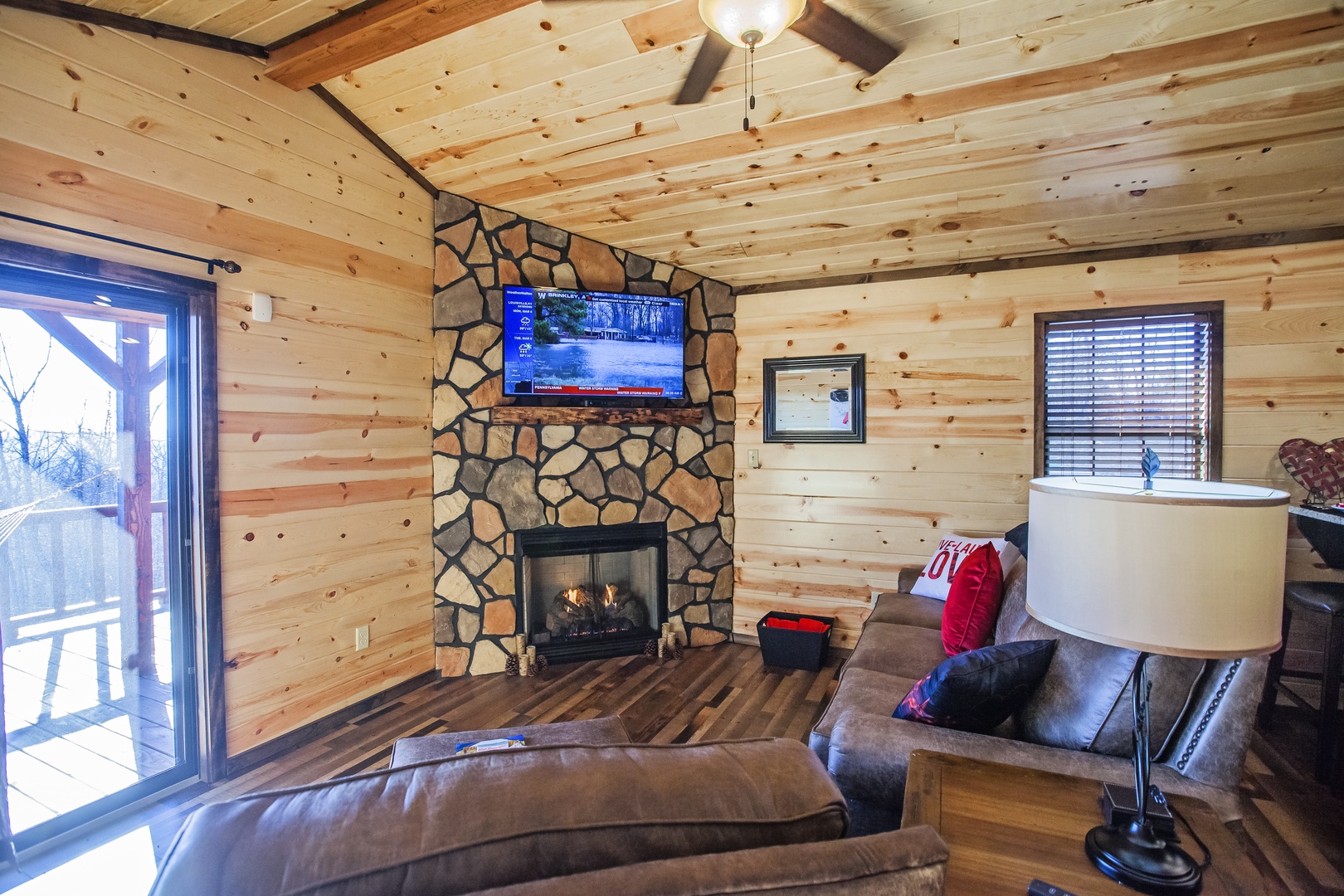 Cozy up in your rustic living room featuring a stunning stone fireplace, flat-screen TV, and comfortable leather seating.