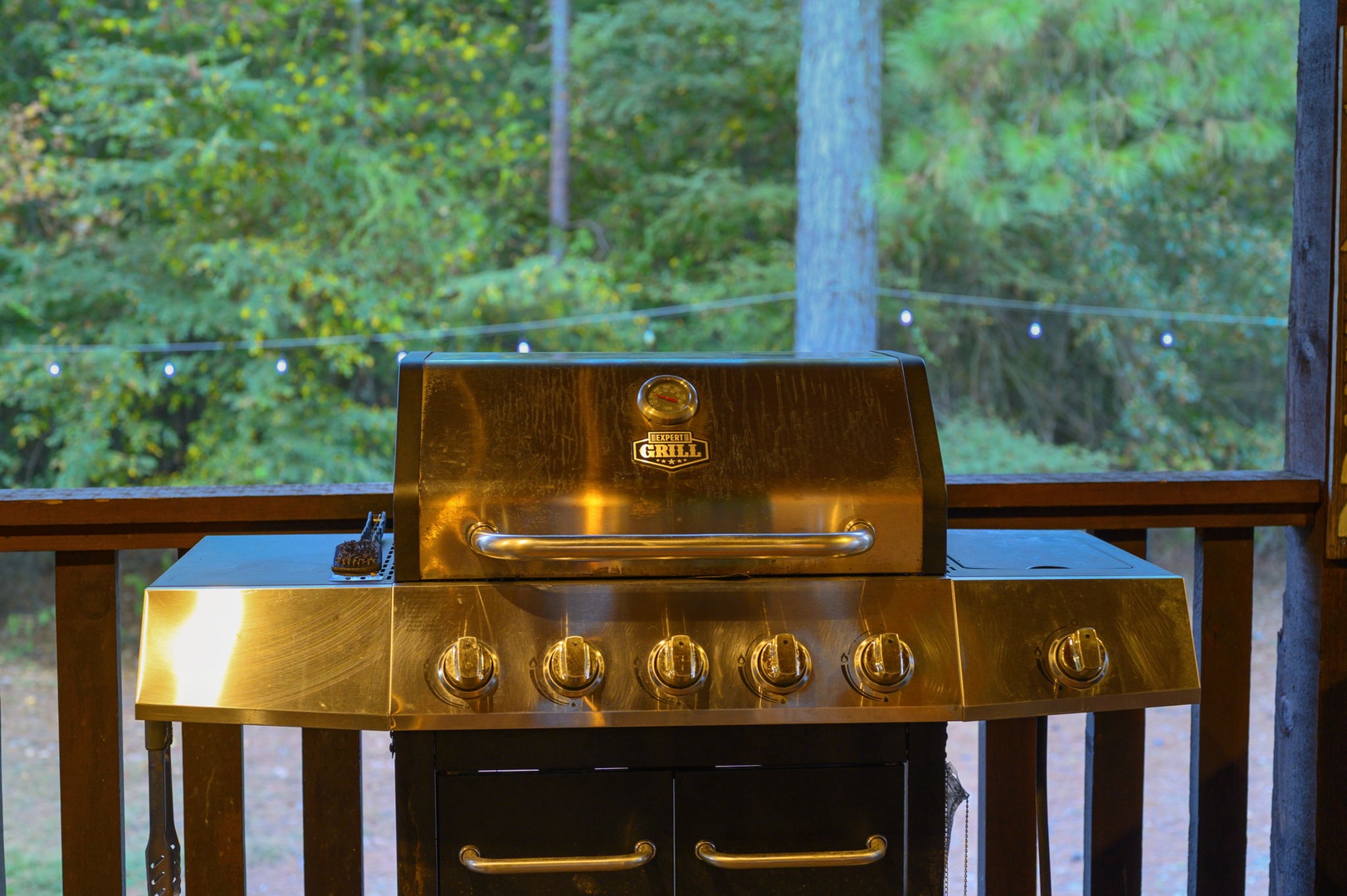A gleaming grill awaits your culinary adventures on the deck, surrounded by lush forest views for the perfect outdoor cooking experience.