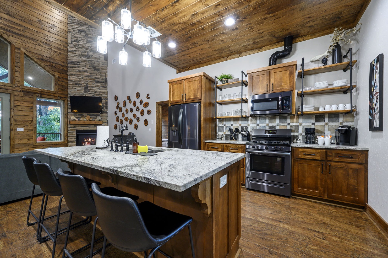 Picture yourself creating memorable meals in this beautifully rustic kitchen, where warm wood meets modern appliances under a stunning vaulted ceiling, all while the fireplace crackles nearby.