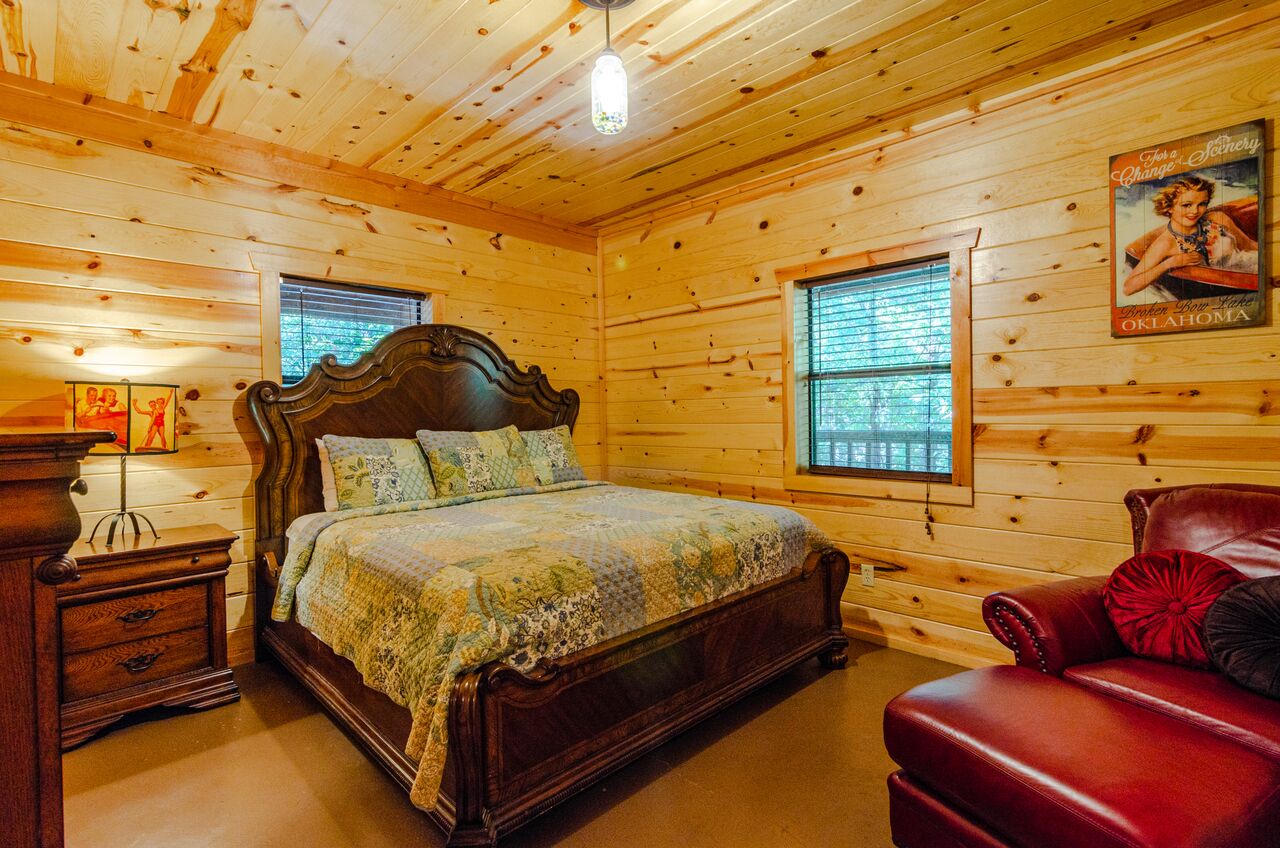 Sink into the rich warmth of this charming bedroom, where knotty pine walls surround you and a handsome bed awaits beneath vaulted ceilings. You'll love the cozy seating nook and vintage décor touches.