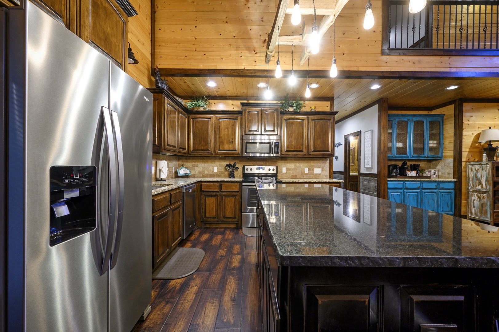 Cook your favorite meals in this spacious kitchen, featuring rich wood cabinetry, gleaming granite counters, and stainless steel appliances. The warm wood ceilings and open layout invite you to gather and share memorable moments.