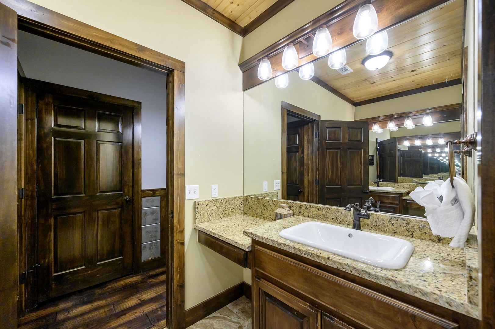 Step into your beautifully appointed bathroom, where warm wood tones and elegant granite countertops create a welcoming retreat for your morning routine.