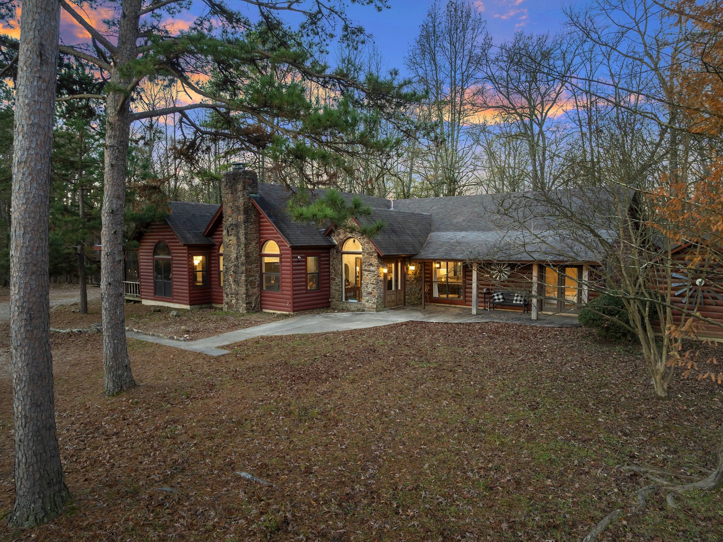 Rustic log cabin surrounded by towering trees offers a peaceful woodland retreat with warm lighting and natural charm.