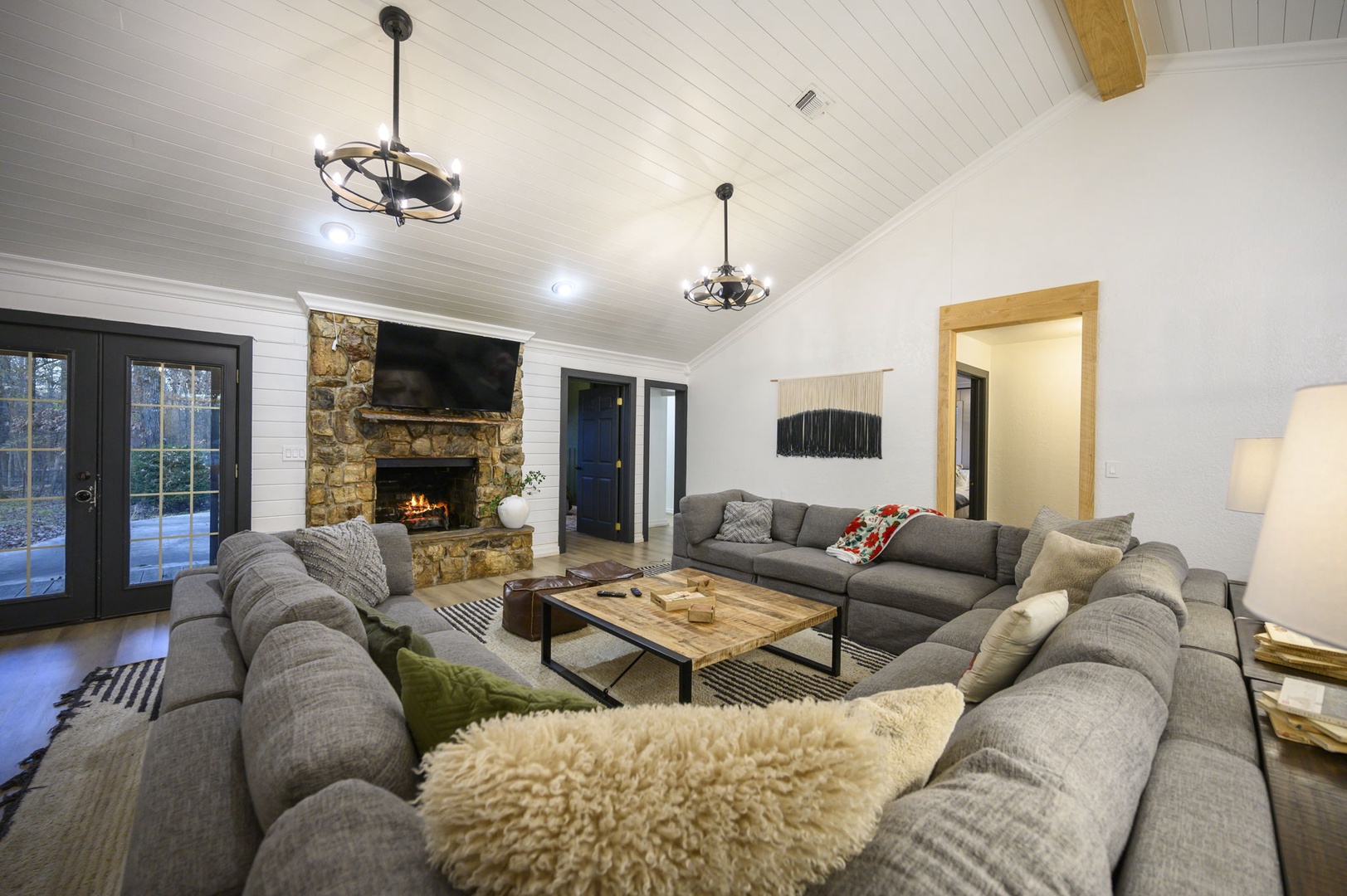 Sink into plush sectional seating by your crackling stone fireplace, where vaulted ceilings and warm lighting create the perfect gathering space for memorable evenings.