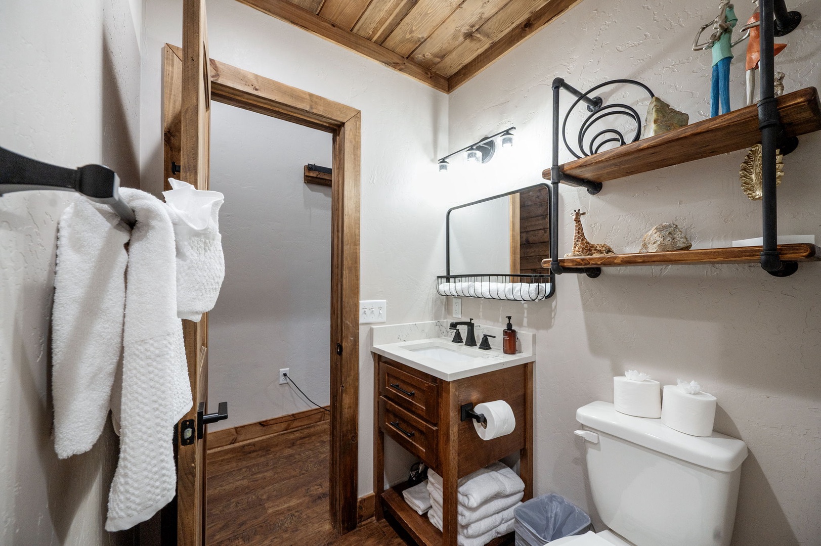 Freshen up in your private bathroom featuring a cozy wood-beamed ceiling, rustic vanity, and thoughtful touches like plush towels and charming décor that make it feel like home.