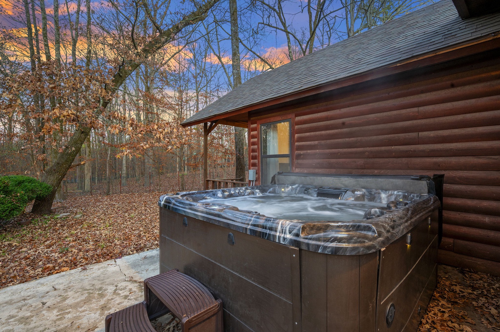 Soak in your private hot tub while surrounded by serene autumn woods and the warm glow of sunset.