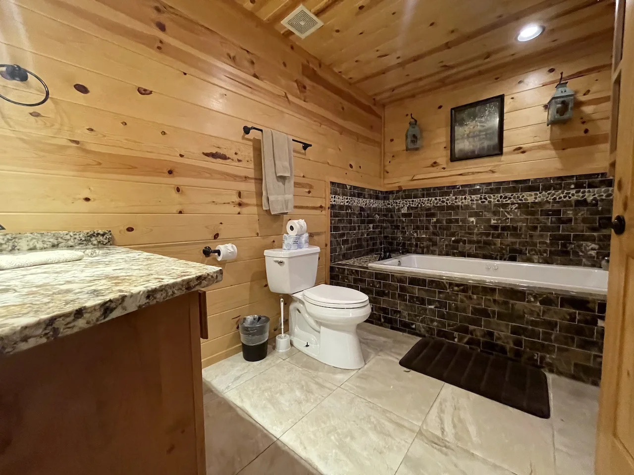 Soak away your cares in this rustic bathroom, where warm knotted pine walls meet elegant stone tile. Your deep soaking tub awaits after a day of adventure.