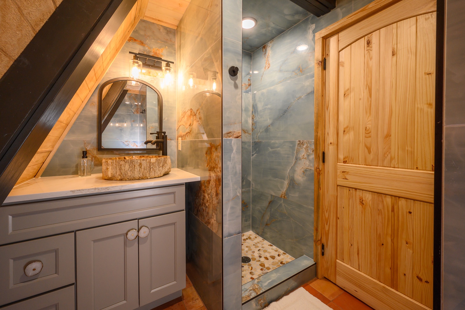 Unwind in your private bathroom, where a striking stone vessel sink and elegant glass-enclosed shower blend rustic charm with modern luxury.