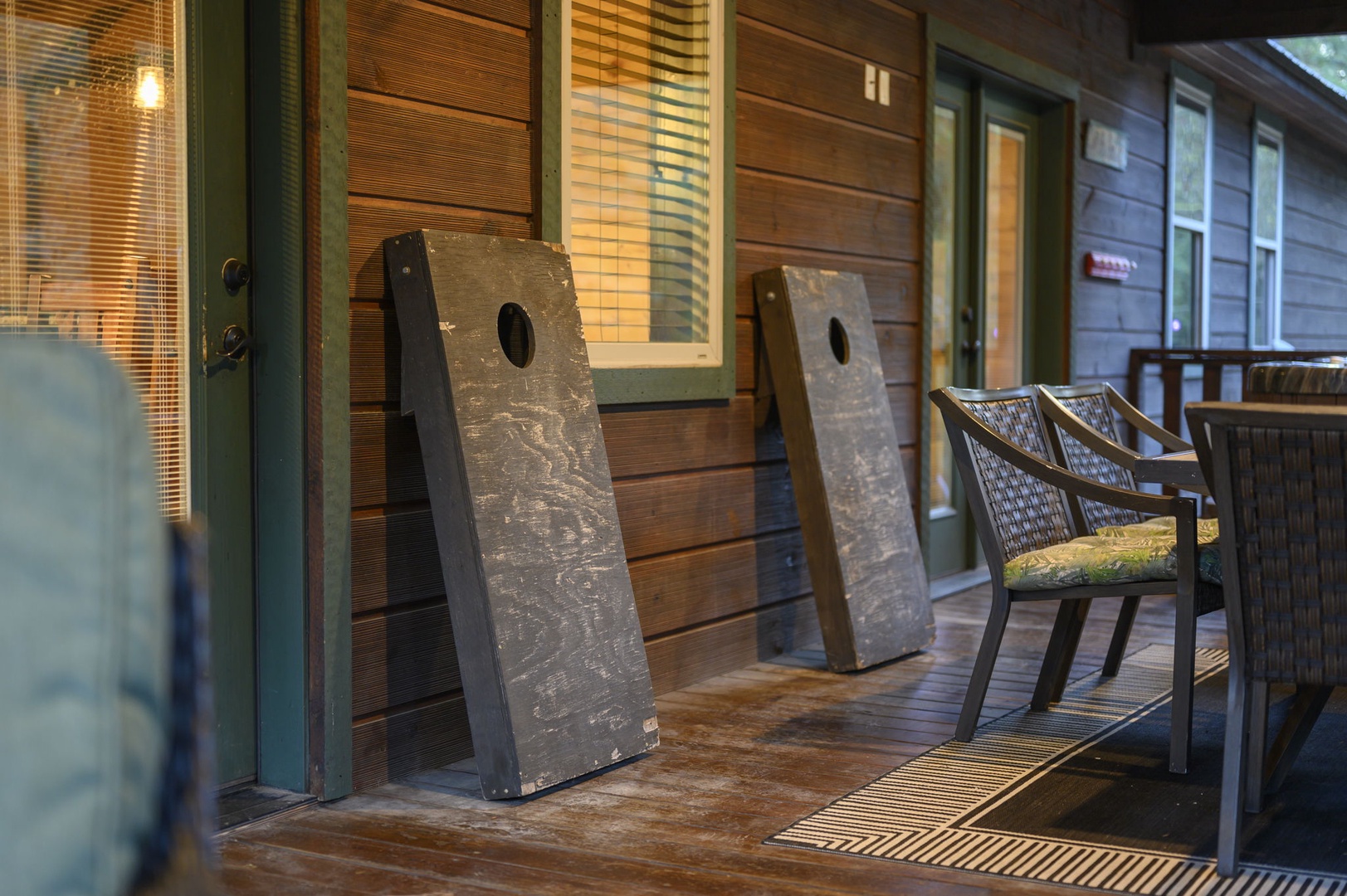 A cozy cabin facade with warm wood tones and green trim welcomes you to your retreat. Relax on your private porch and enjoy friendly games of cornhole under the glow of evening light.