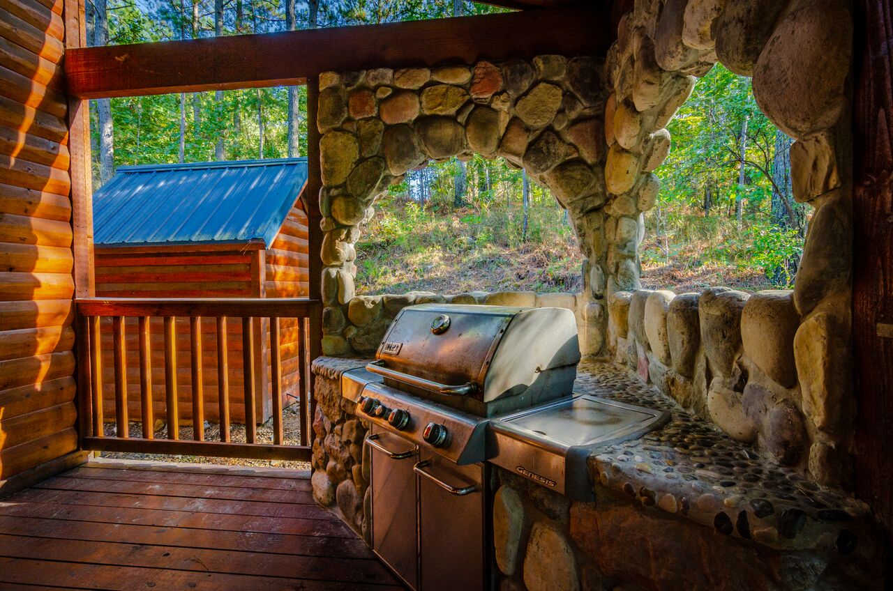 Rustic stone archway frames your private grill station, where natural woodlands create a serene backdrop for memorable outdoor meals surrounded by towering trees.