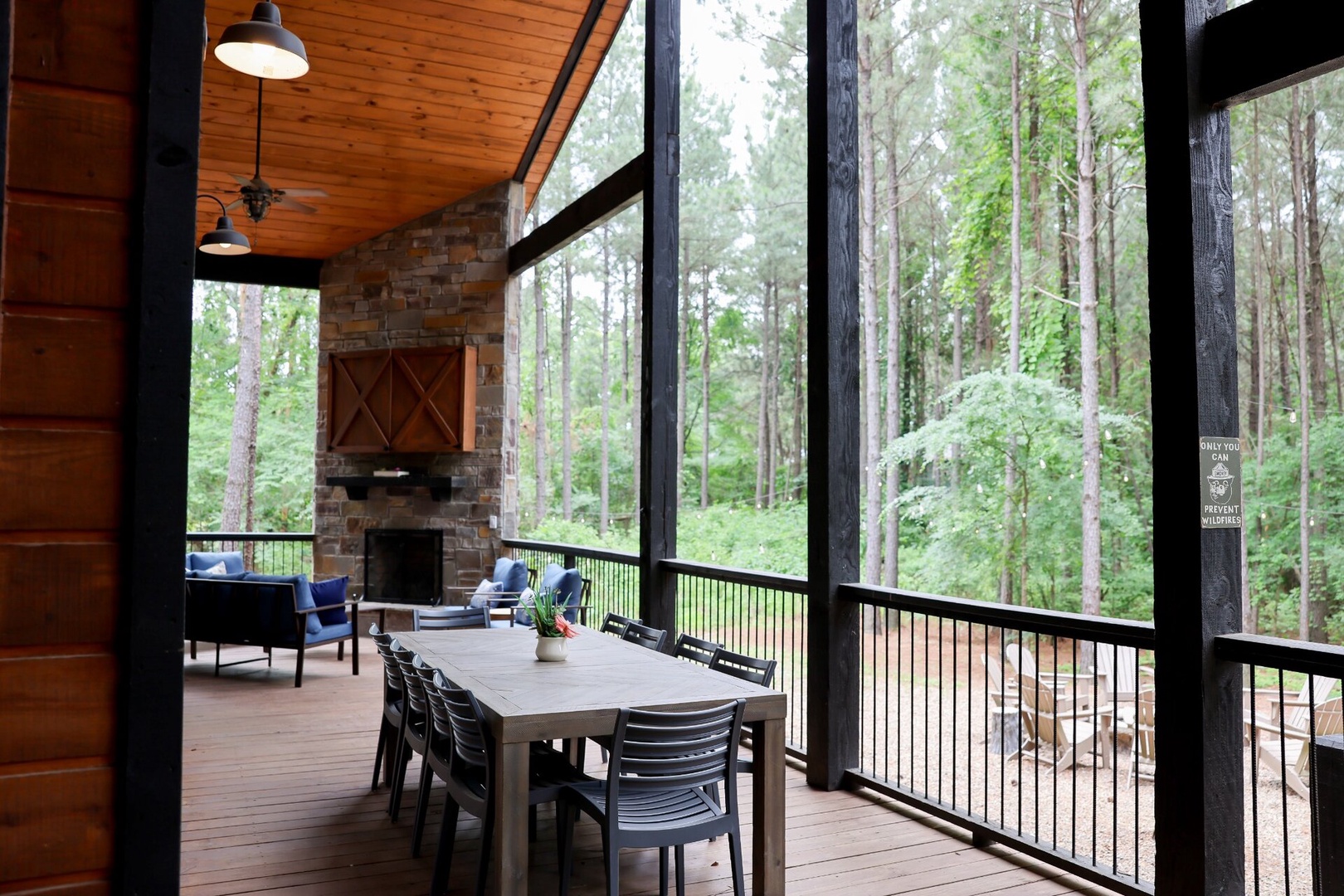 This peaceful woodland retreat features towering pines framing your private porch, where cozy seating and a glowing fireplace invite you to unwind with the forest as your backdrop.