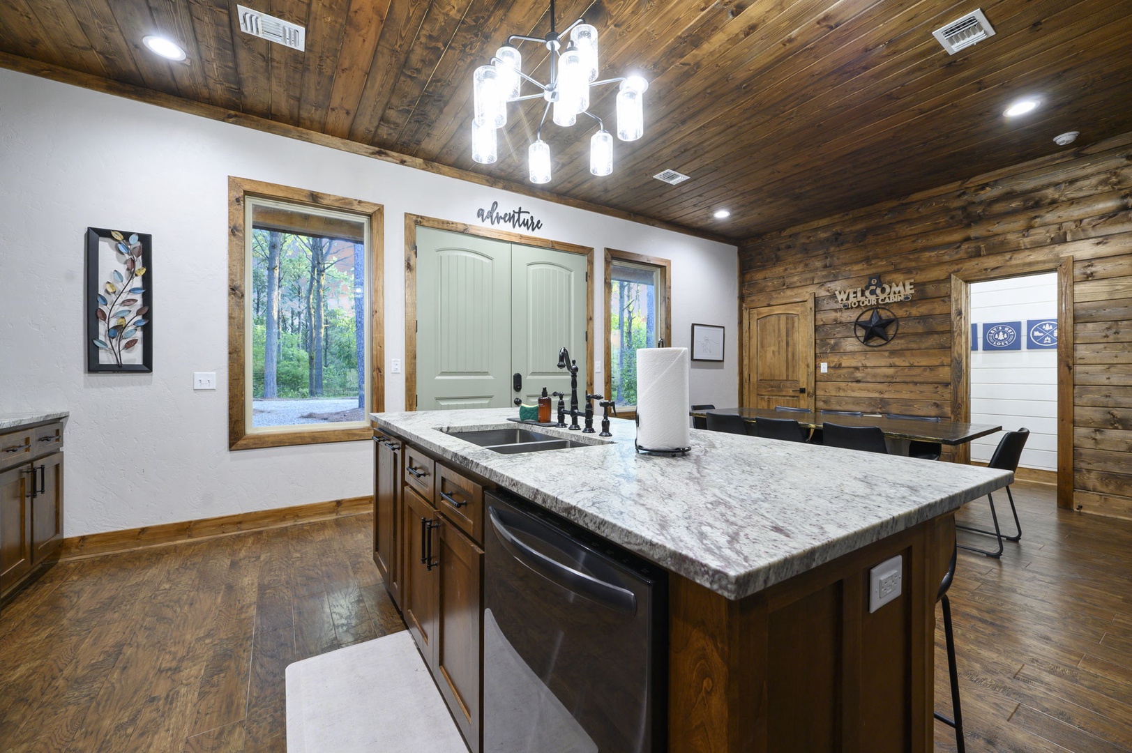Your fully equipped kitchen invites you to cook and connect, with rustic wood ceilings, a generous island, and windows framing peaceful woodland views.