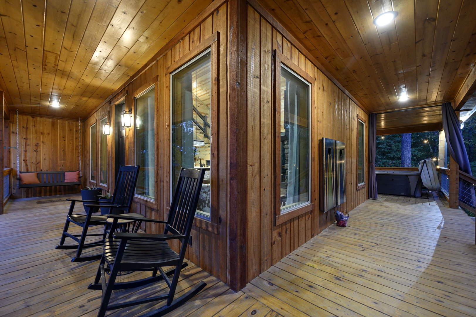 Step onto your spacious covered deck where rustic wood wraps you in warmth and classic rocking chairs invite quiet evenings under soft ambient lighting—ideal for unwinding with a glass of wine.