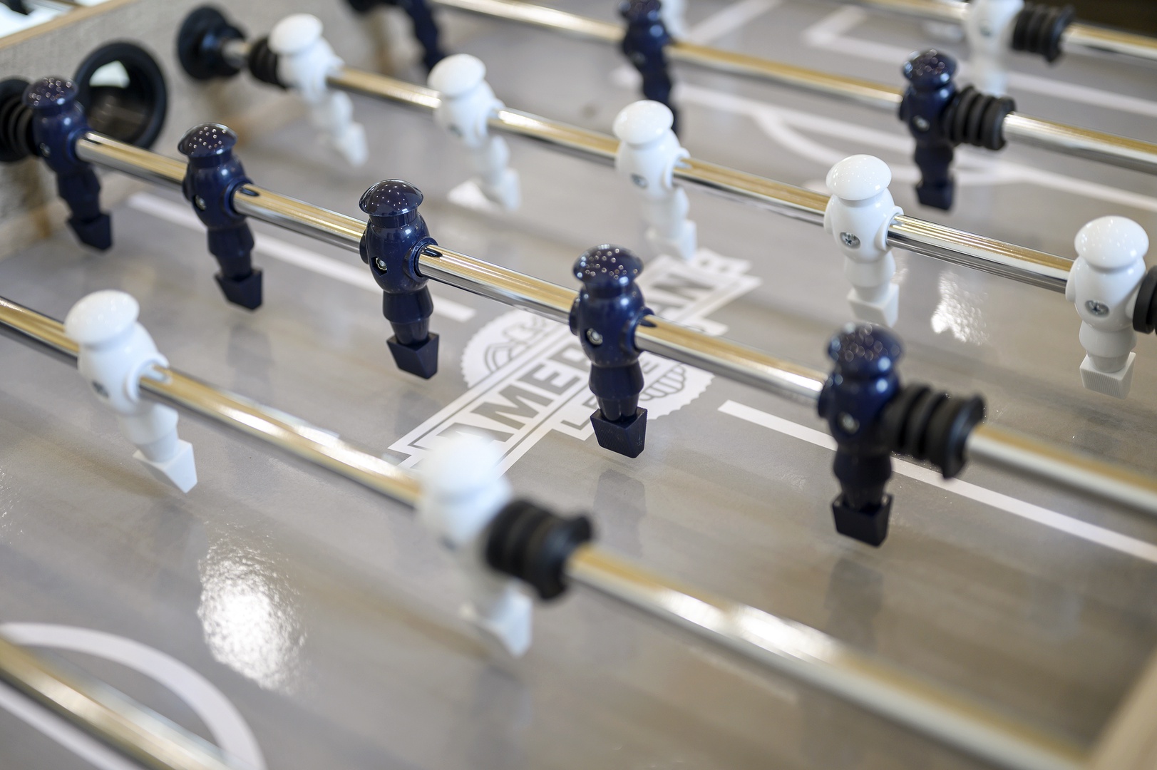 Challenge friends to a game on this sleek foosball table with navy and white players ready for action.