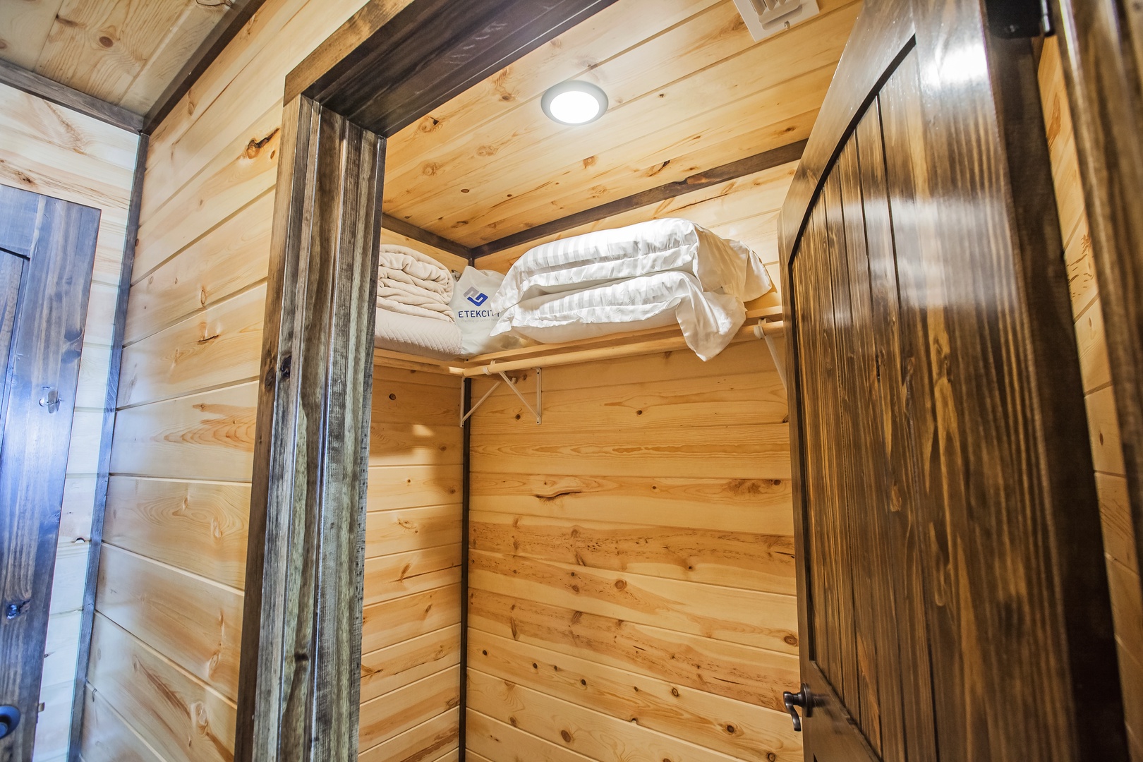 Step into your cozy wooden sanctuary where extra linens await on the convenient shelf, ready for your mountain retreat comfort.